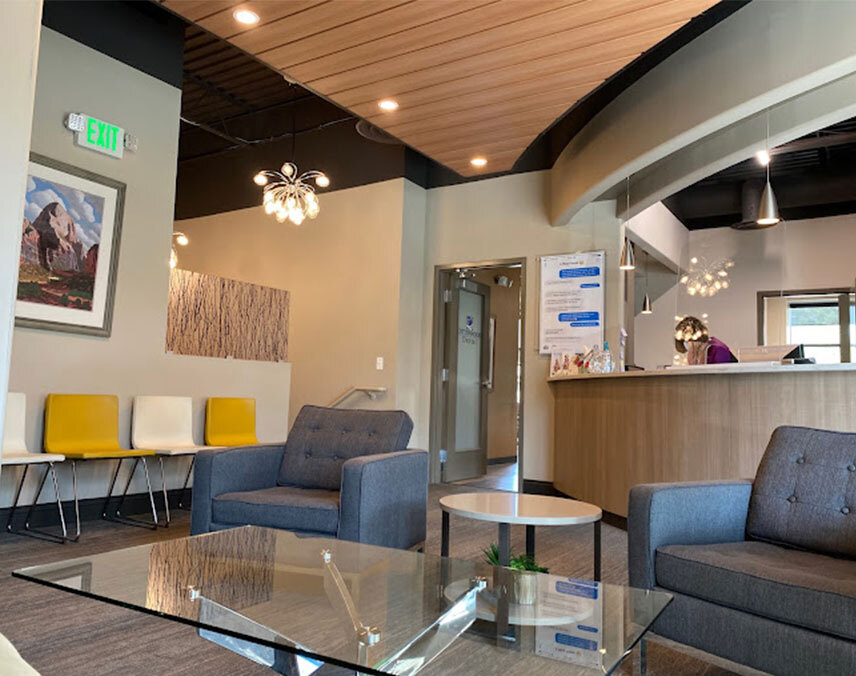 Modern dental office waiting room with blue chairs, wood ceiling, and reception desk in Salt Lake City.