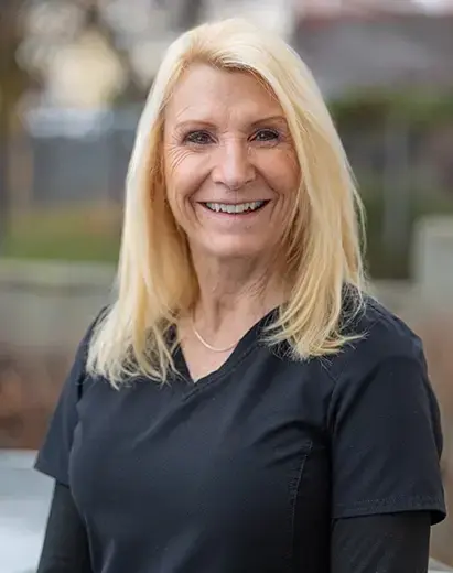 Smiling dental professional with blonde hair wearing black scrubs at Salt Lake City practice.